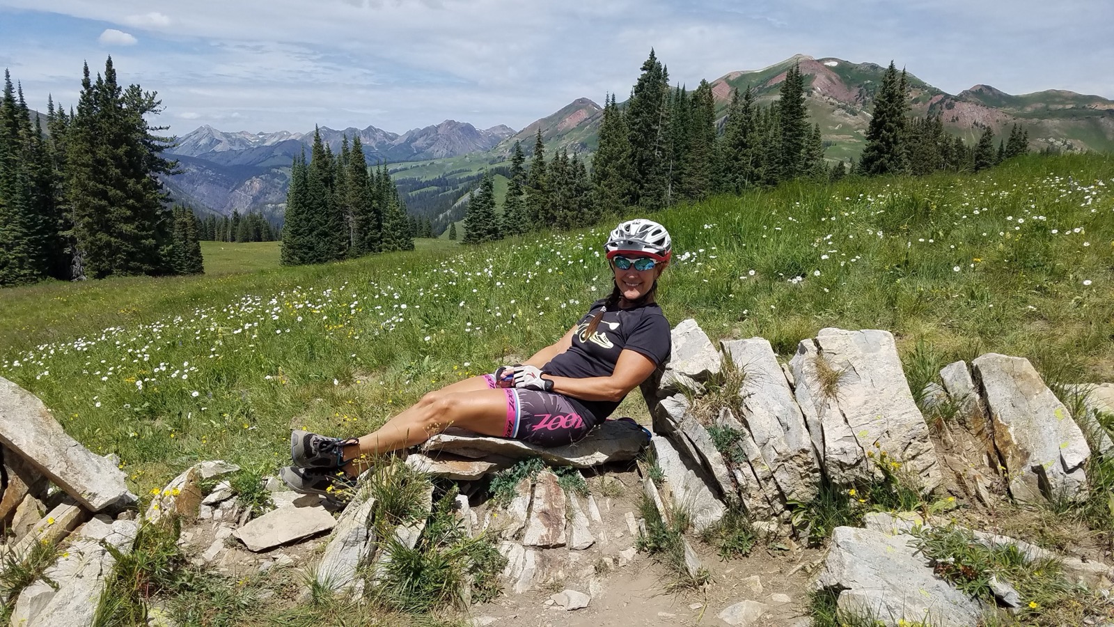 Alisa resting against trail rocks in a wildflower meadow at 11,000 feet in the Colorado high country